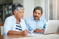 Older couple looking at paperwork and laptop