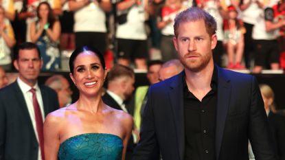 Meghan Markle wears a green strapless dress while Prince Harry wears a black suit with black shirt underneath