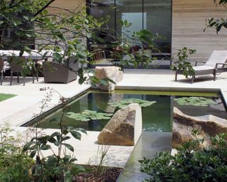 modern water feature surrounded by sleep paving and large boulders