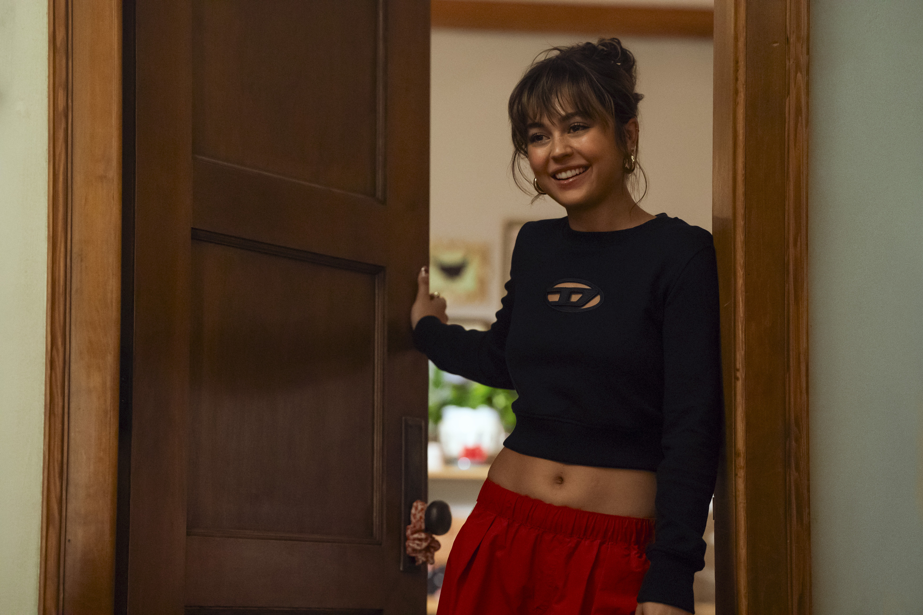 Allie Hayes (Mika Abdalla) smiles while opening the door to her dorm in OFF CAMPUS