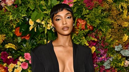 A model, Jourdan Dunn, stands in front of a wall of flowers showing off a new short haircut.