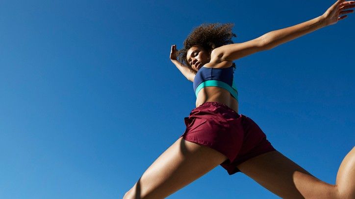 A woman wearing running shorts against a blue sky