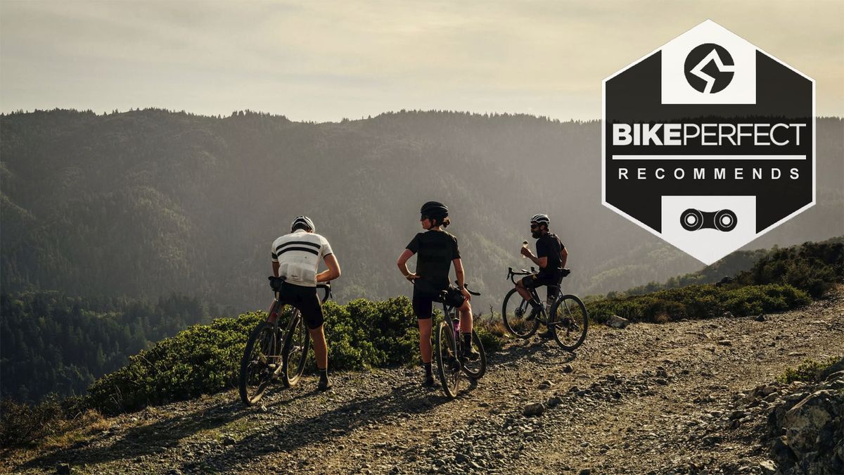 Three gravel cyclists - two male, one female - resting at the top of a gravel climb and looking into the distance