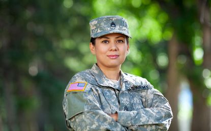 Female soldier in uniform standing with arms crossed