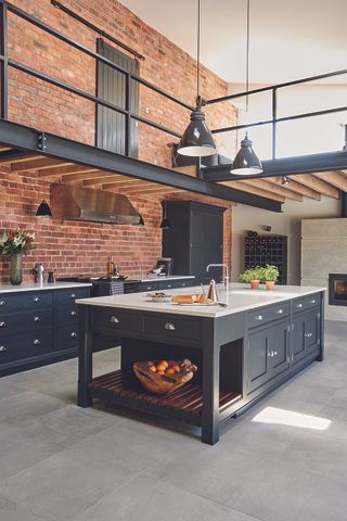 A large dark grey kitchen with an exposed brick wall