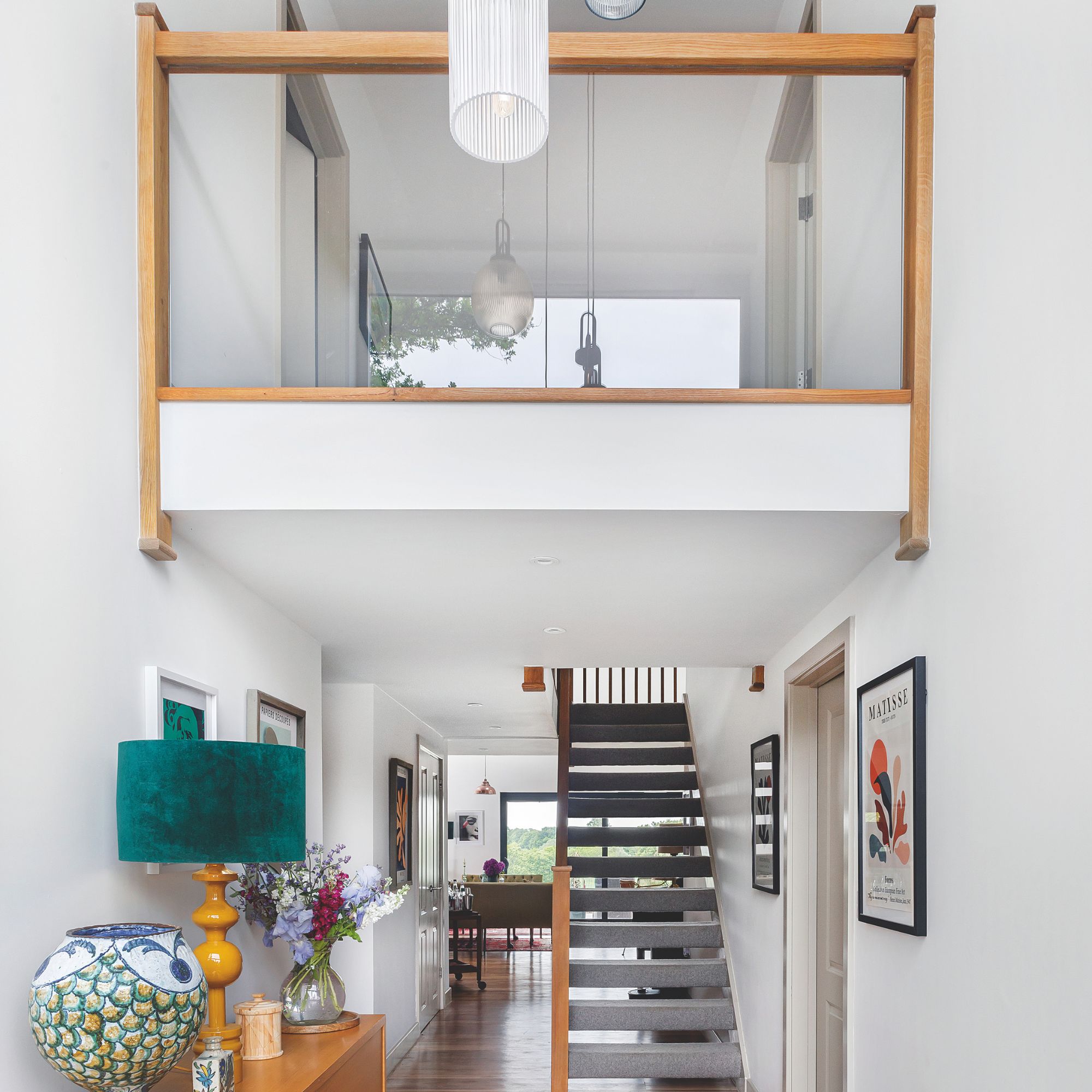 White hallway with glass banister and wood accents