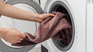 A towel being loaded into a washing machine