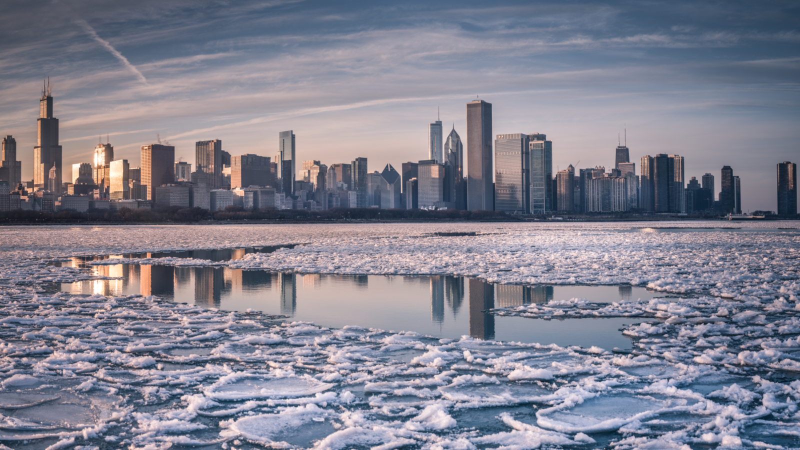 A photo of ice on the surface of Lake Michigan with the Chicago skyline in the distance