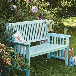 Blue-green painted garden bench on lawn