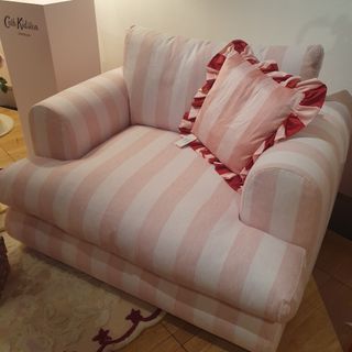 A pink and white striped love seat by Cath Kidston with a striped ruffled cushion