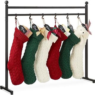 Red, gree and white knitted stockings hanging from a black metal post. 