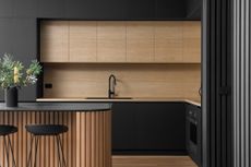 A kitchen with black cabinets and wooden island 