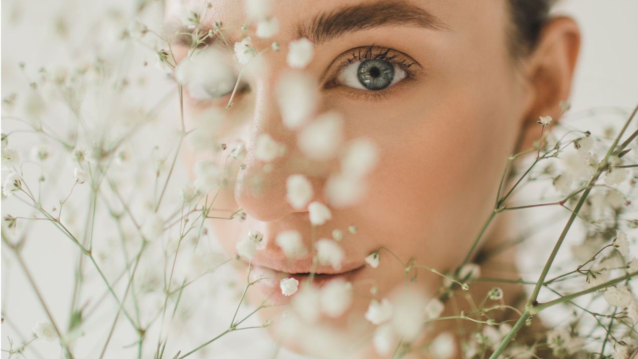 Best musk perfumes: Woman with white flowers in front of her face