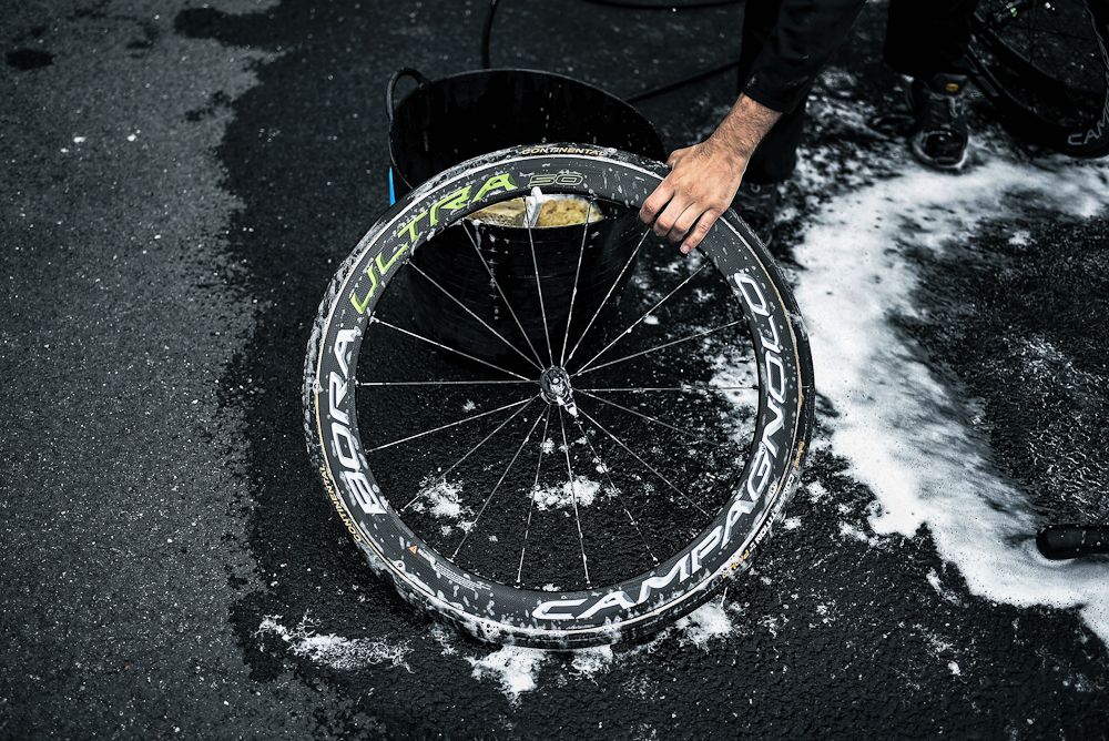 A bicycle mechanic cleans the wheel of a bike in front of the hotel of Spain's Movistar cycling team in Coutanceson a day before the start of the 2016 Tour de France