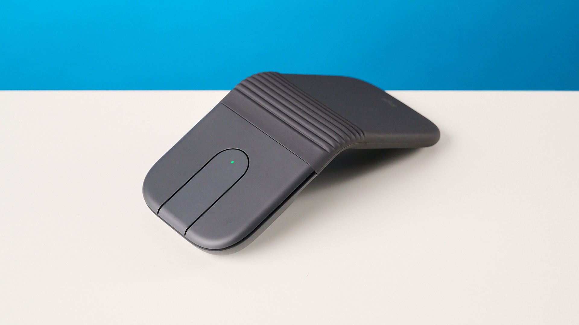 Logitech Mobi Fold mouse in graphite photographed in front of a blue background
