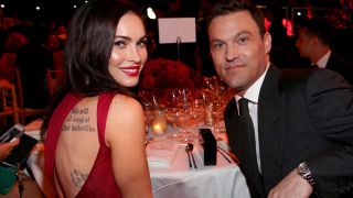 Megan Fox and Brian Austin Green, she's in a red dress with back tattoos, he's in a suit.