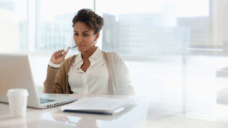 A woman chews on a pen and thinks.