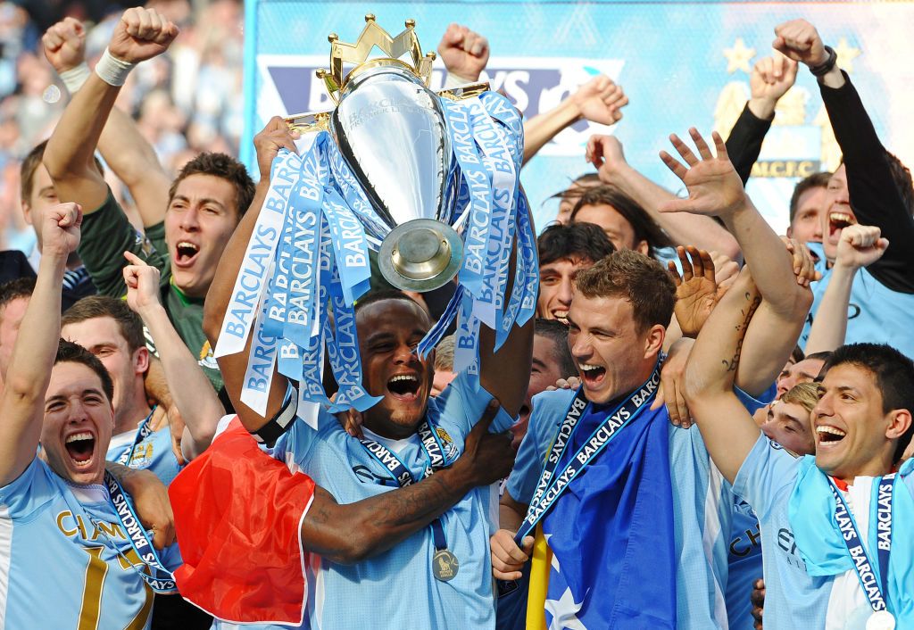 TOPSHOT - Manchester City&#039;s Belgian captain Vincent Kompany lifts the Premier league trophy, and celebrates with Bosnian striker Edin Dzeko (2nd R), Argentinian striker Sergio Aguero (R) and French midfielder Samir Nasri (L) after their 3-2 victory over Queens Park Rangers in the English Premier League football match between Manchester City and Queens Park Rangers at The Etihad stadium in Manchester, north-west England on May 13, 2012. Manchester City won the game 3-2 to secure their first title since 1968. This is the first time that the Premier league title has been decided on goal-difference, Manchester City and Manchester United both finishing on 89 points. AFP PHOTO/PAUL ELLIS RESTRICTED TO EDITORIAL USE. No use with unauthorized audio, video, data, fixture lists, club/league logos or &#039;live&#039; services. Online in-match use limited to 45 images, no video emulation. No use in betting, games or single club/league/player publications. (Photo by PAUL ELLIS / AFP) (Photo by PAUL ELLIS/AFP via Getty Images)