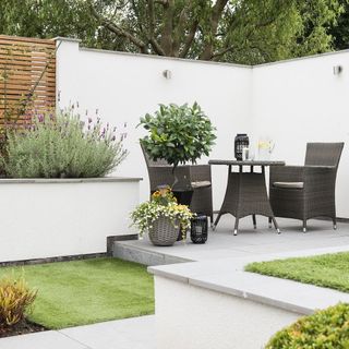 garden with white wall grey chair and green grass