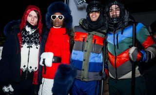 Models wearing winter clothing for skiing, red, blue and grey striped jackets with fur hats