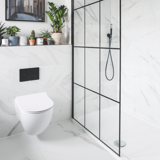 Bathroom makeover. Contemporary monochrome and streamlined bathroom with marble wall tiles and black accents. Shower screen. Bathroom renovation in a five bedroom detached house in East Sussex, home of Jennie Roe.