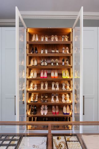closet shoe storage with glass doors, LED lighting, white closet doors each side, jewellery storage in foreground