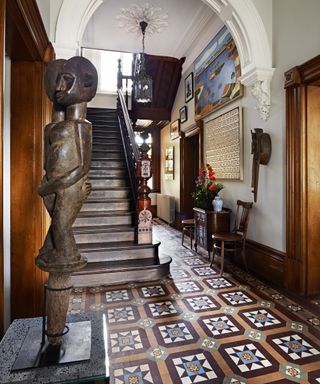 Victorian hallway tiles in yellow, brown and blue in an ornate entryway with arched ceilings and wooden doorways