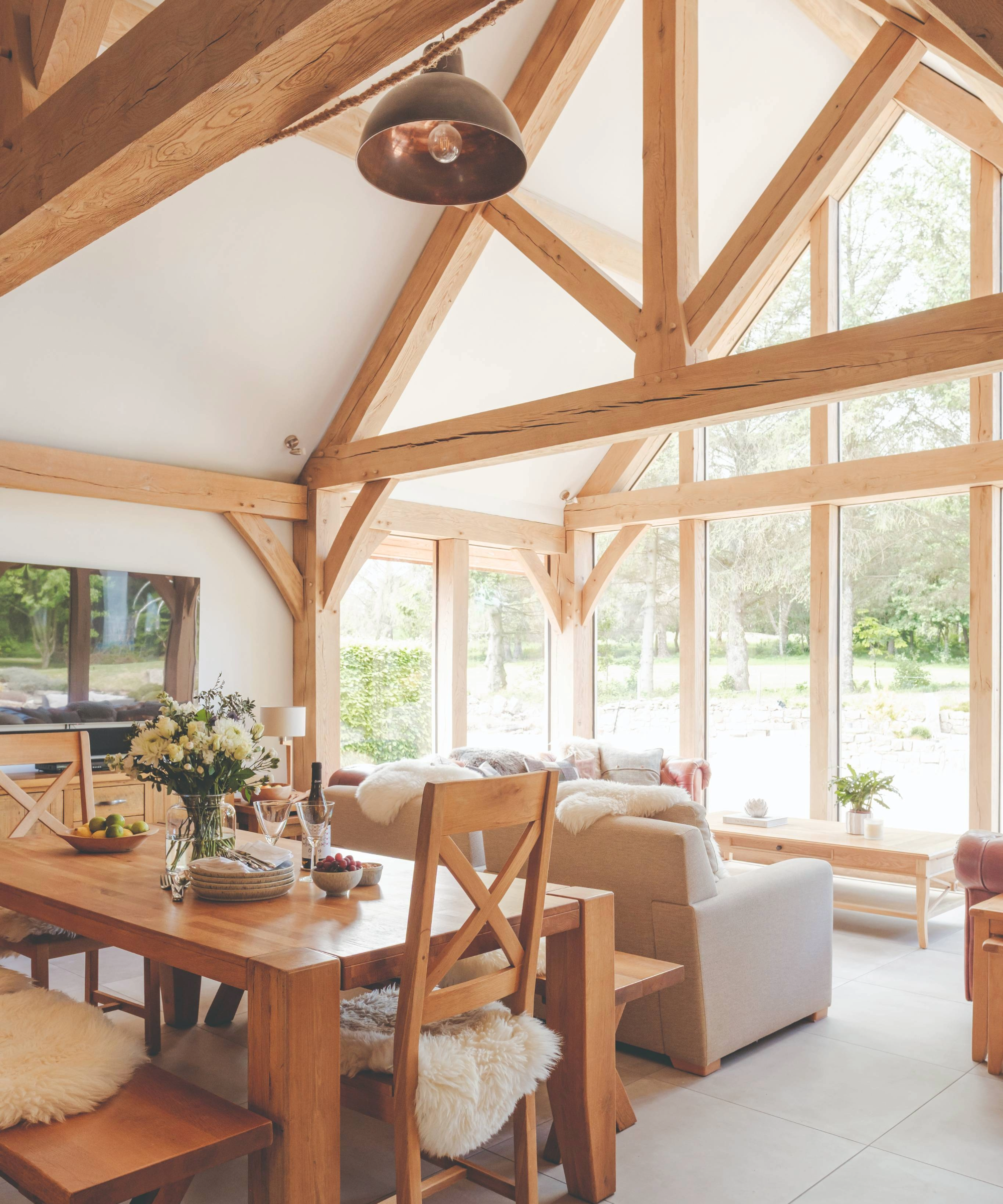 Open plan living and dining area with wood beams and floor to ceiling windows