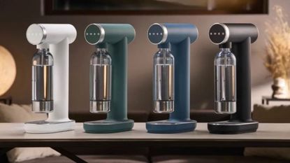Smeg Soda Makers in four colors, lined up on a modern kitchen counter