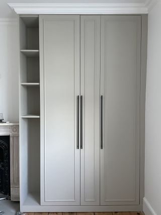 An IKEA PAX wardrobe painted a light grey with added trim and integrated shelving