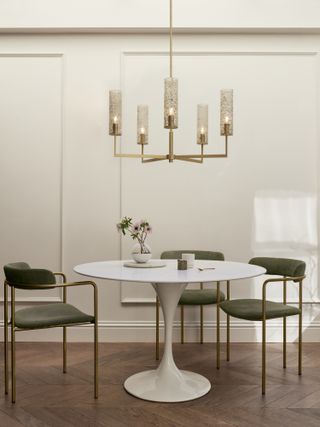 A white dining table with a low hanging chandelier