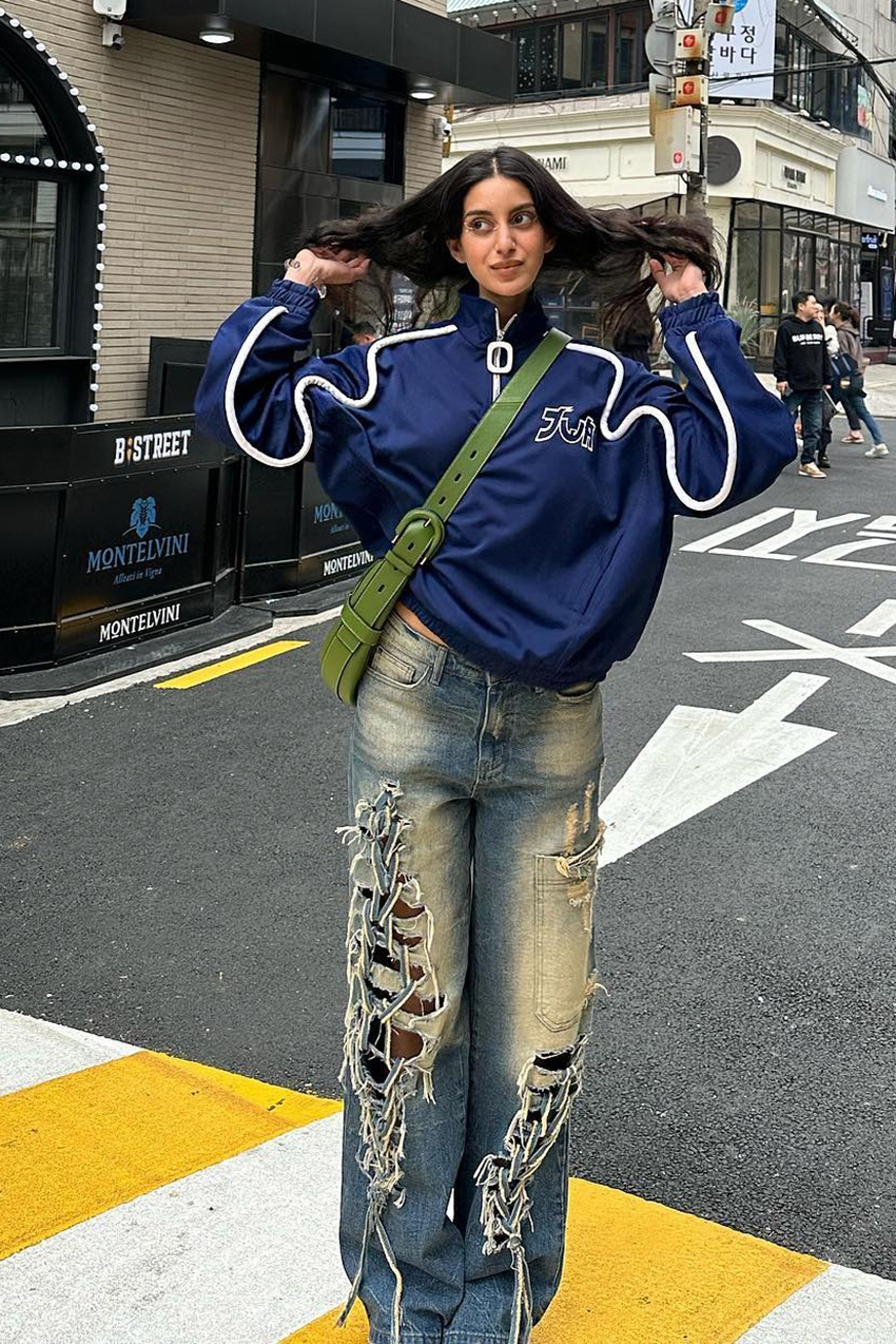 a woman wearing a navy jacket and ripped jeans