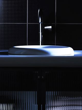Sink with background of black tiles, from Tom Dixon VitrA Liquid bathroom collection
