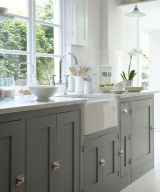 gray kitchen cabinets, view of outside, Shaker style, marble countertops, white floor, white backsplash tiles and walls,