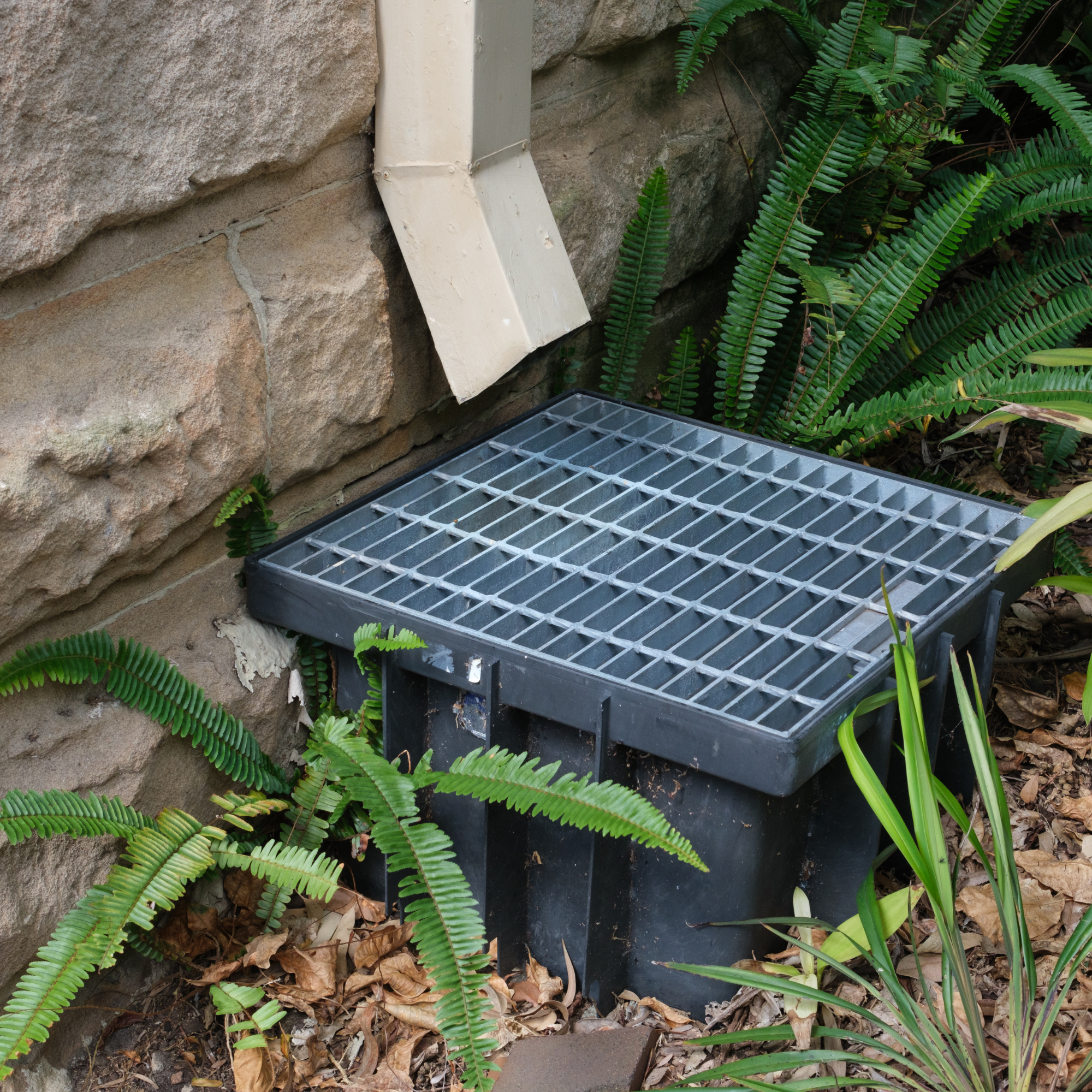 Covered drain against a wall.