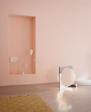 A pink room featuring a silver floor lamp by Louis Poulsen with a rotating disc concealing the light source. When the disk rotates, the light effect is that of moon phases
