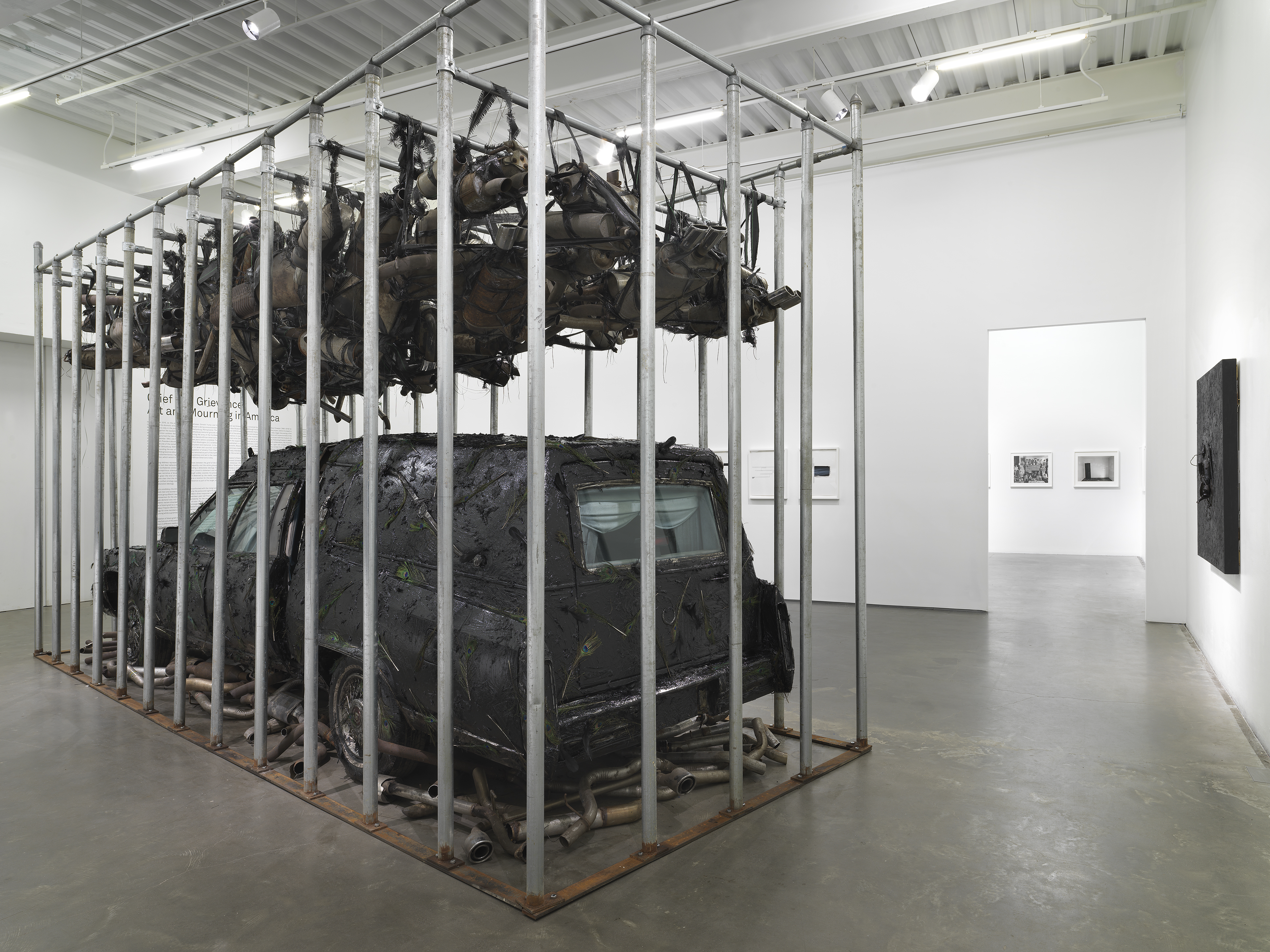 Installation view of Nari Ward, Peace Keeper, 1995. A hearse, mufflers and feathers in a steel cage.