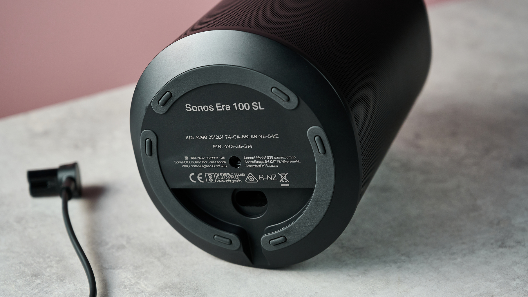 The bottom of the Sonos Era 100 SL, showing the power port and unplugged cable.