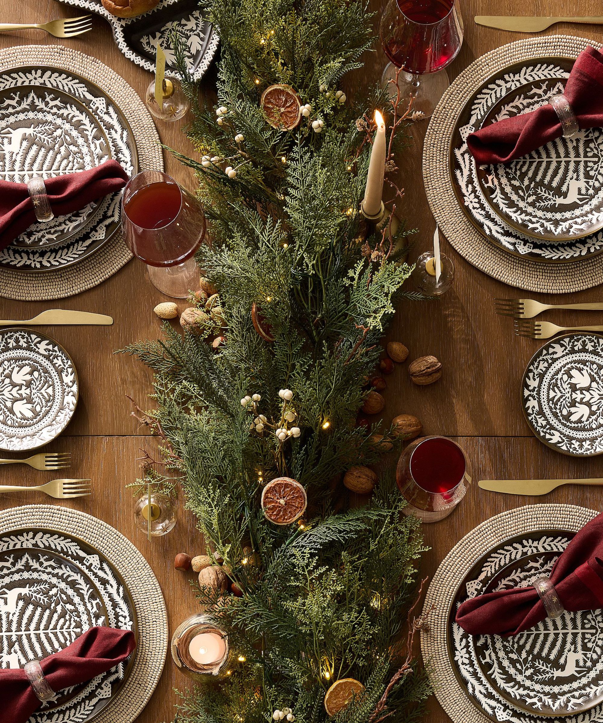 Thanksgiving table with red napkins and a faux greenery and citrus centerpiece