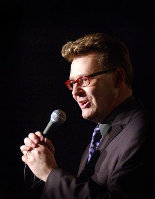 a photo of greg proops the smartest man in the world podcast host holding a microphone