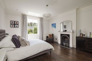 master bedroom with polished dark wooden floor and original fireplace