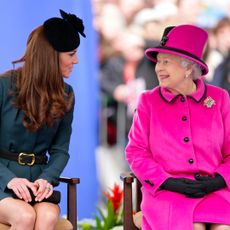 Kate Middleton sitting next to Queen Elizabeth, wearing a bright pink coat and hat