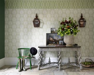 A hallway wallpaper idea with green floral patterned wallpaper and entry table with bright green chair