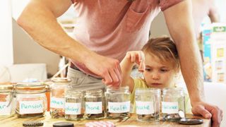 A man and a young child place divide coins into eight jars