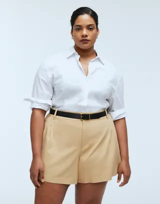 model wears tan shorts with black belt and white button down