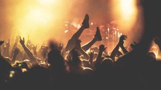 Best concert ticket sites: Crowd shot at a concert with a person crowd surfing and a drum kit in the background