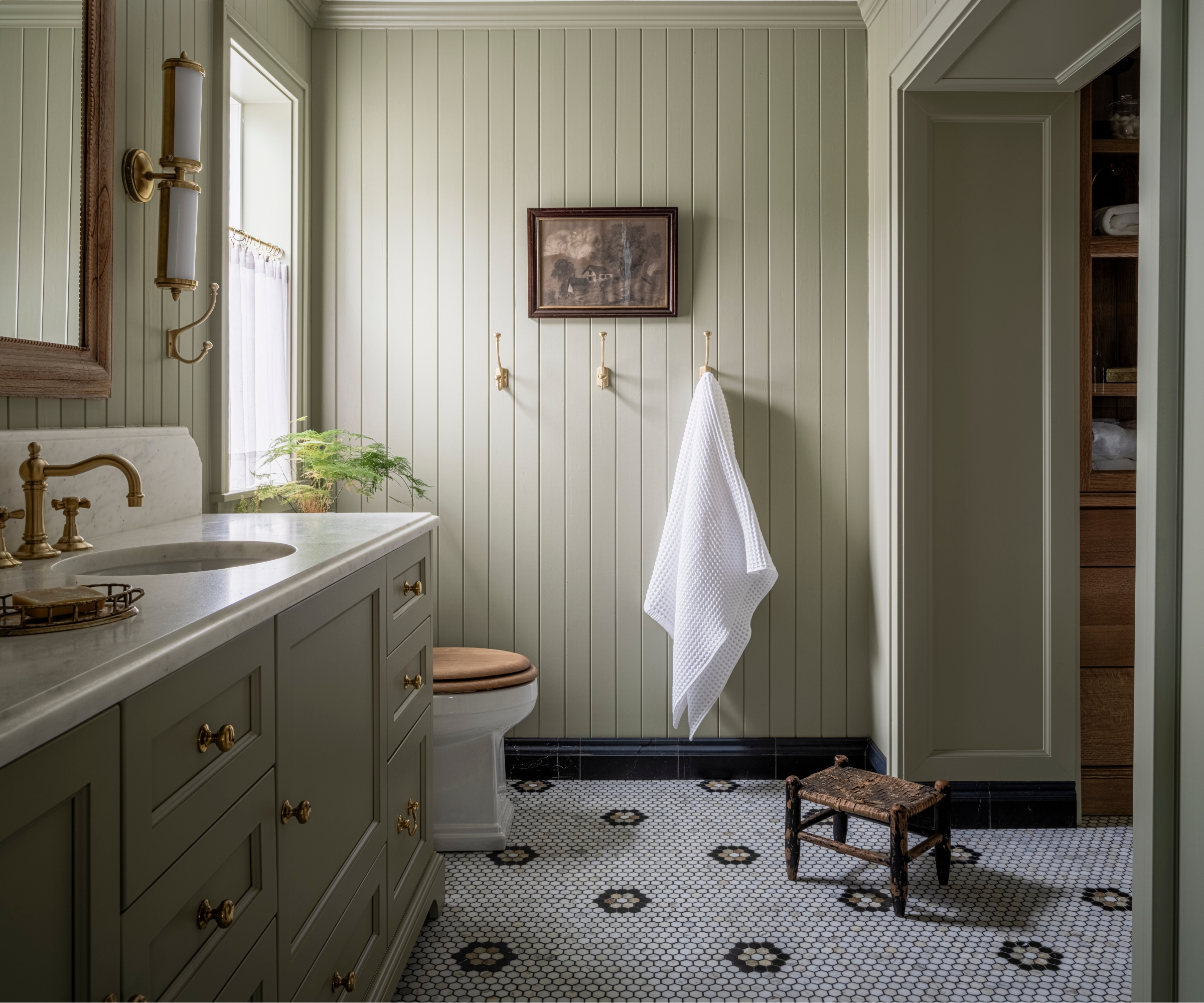 A country bathroom with paneled walls drenched in a soft, earthy green