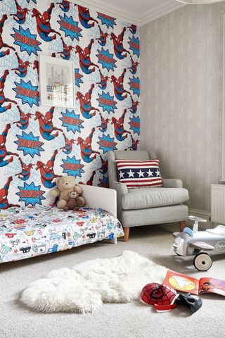 kids' bedroom with spider man wallpaper, colourful bedding, a fluffy rug and a cosy armchair