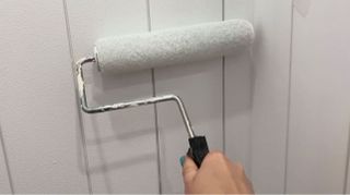 Rolling white paint onto bathroom wall