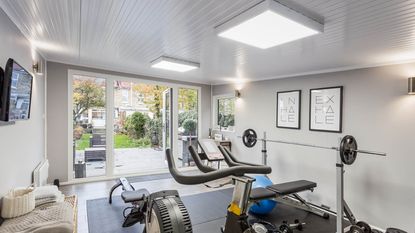 A bright garden room home gym with LED square panel lighting